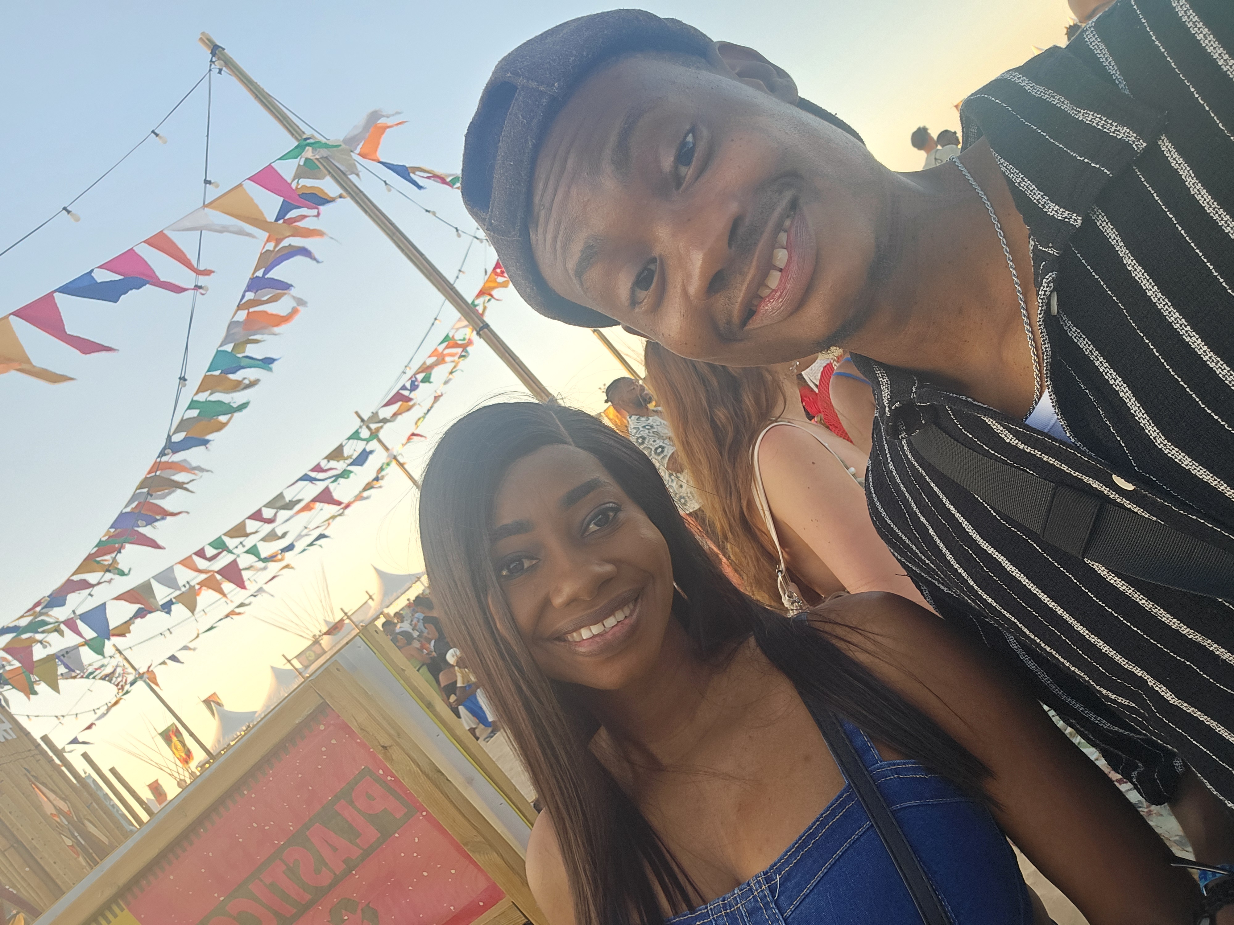 Oluwasefunmi and Olanrewaju smiling outdoors under colorful flags