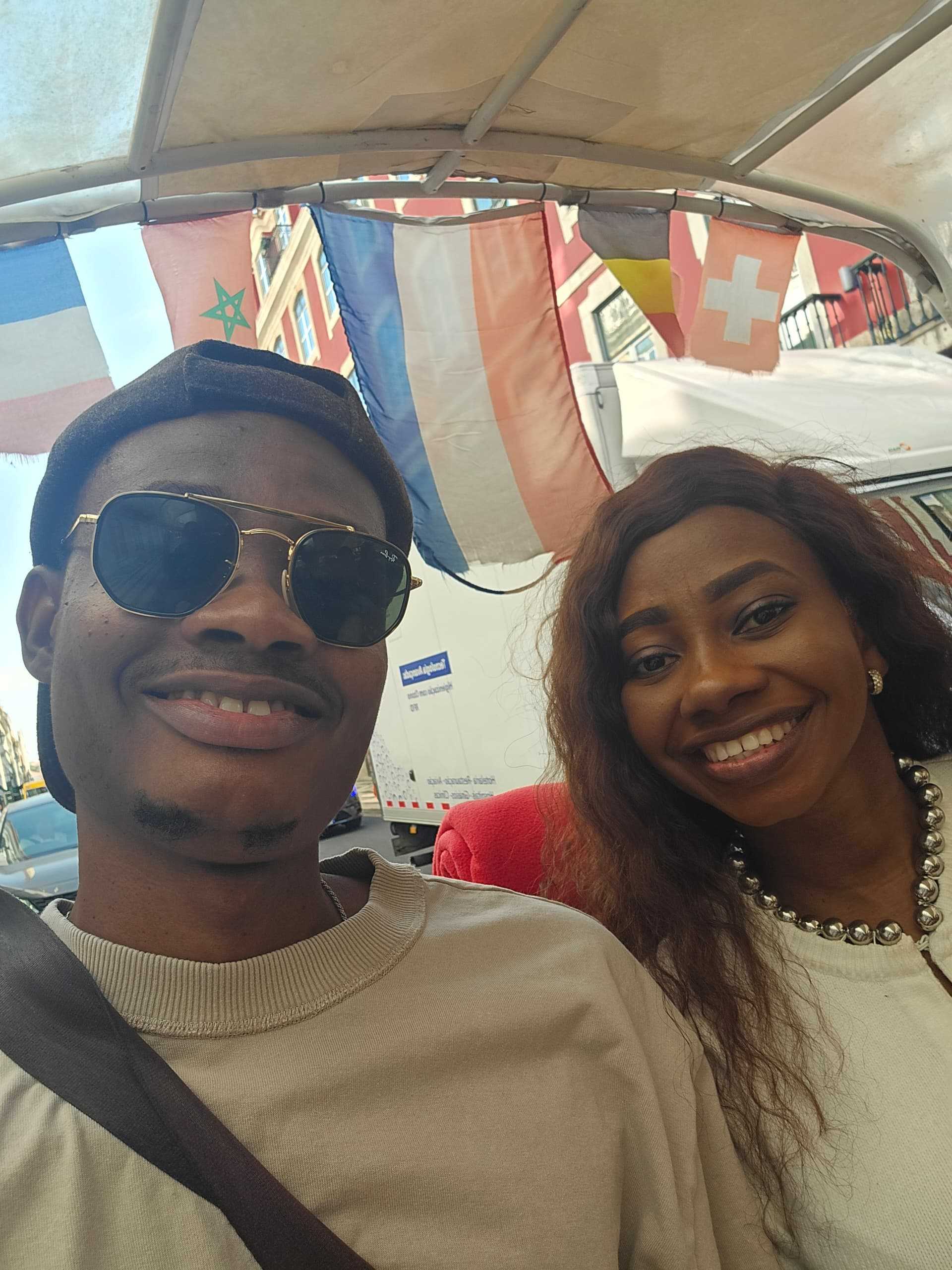 Oluwasefunmi and Olanrewaju smiling under colorful flags